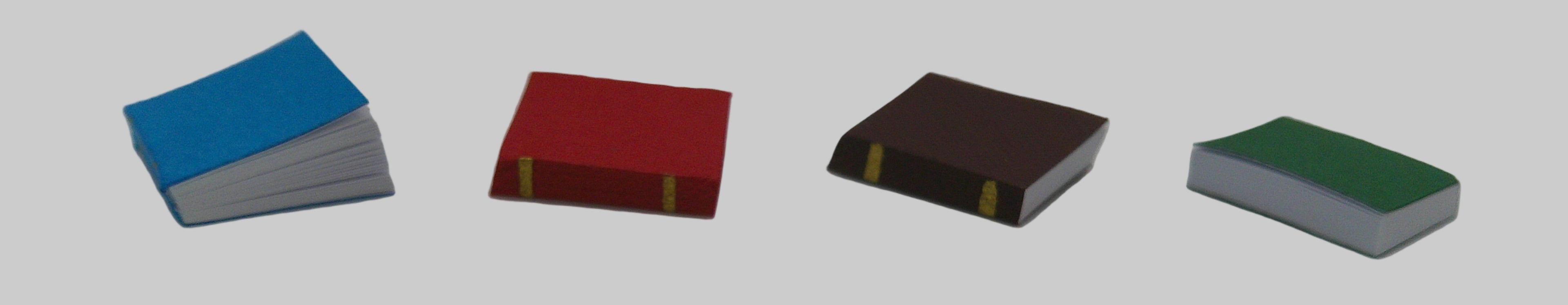 Four small books with different colored covers on a white background