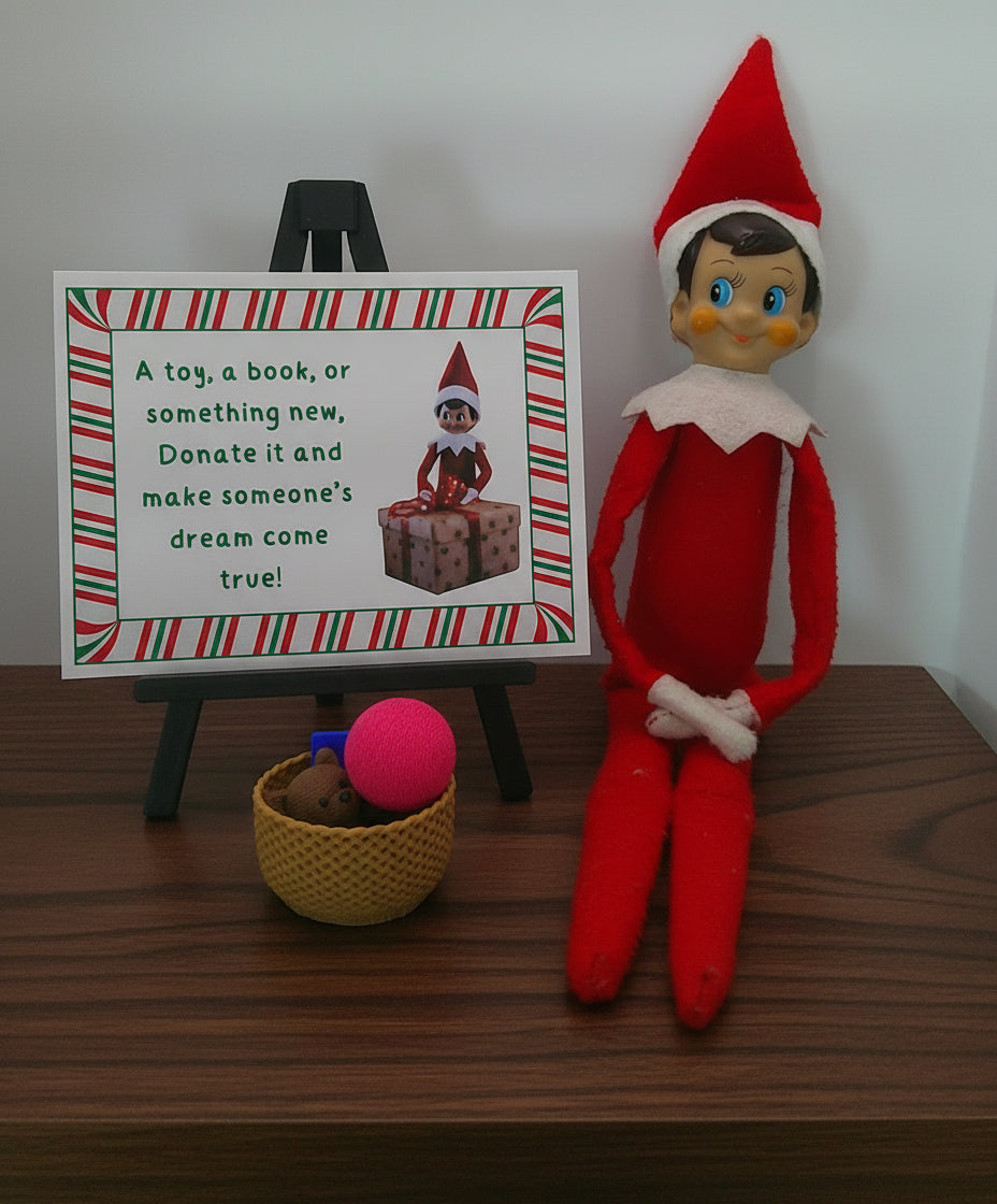 Elf on the Shelf with a sign encouraging toy donations on a white background