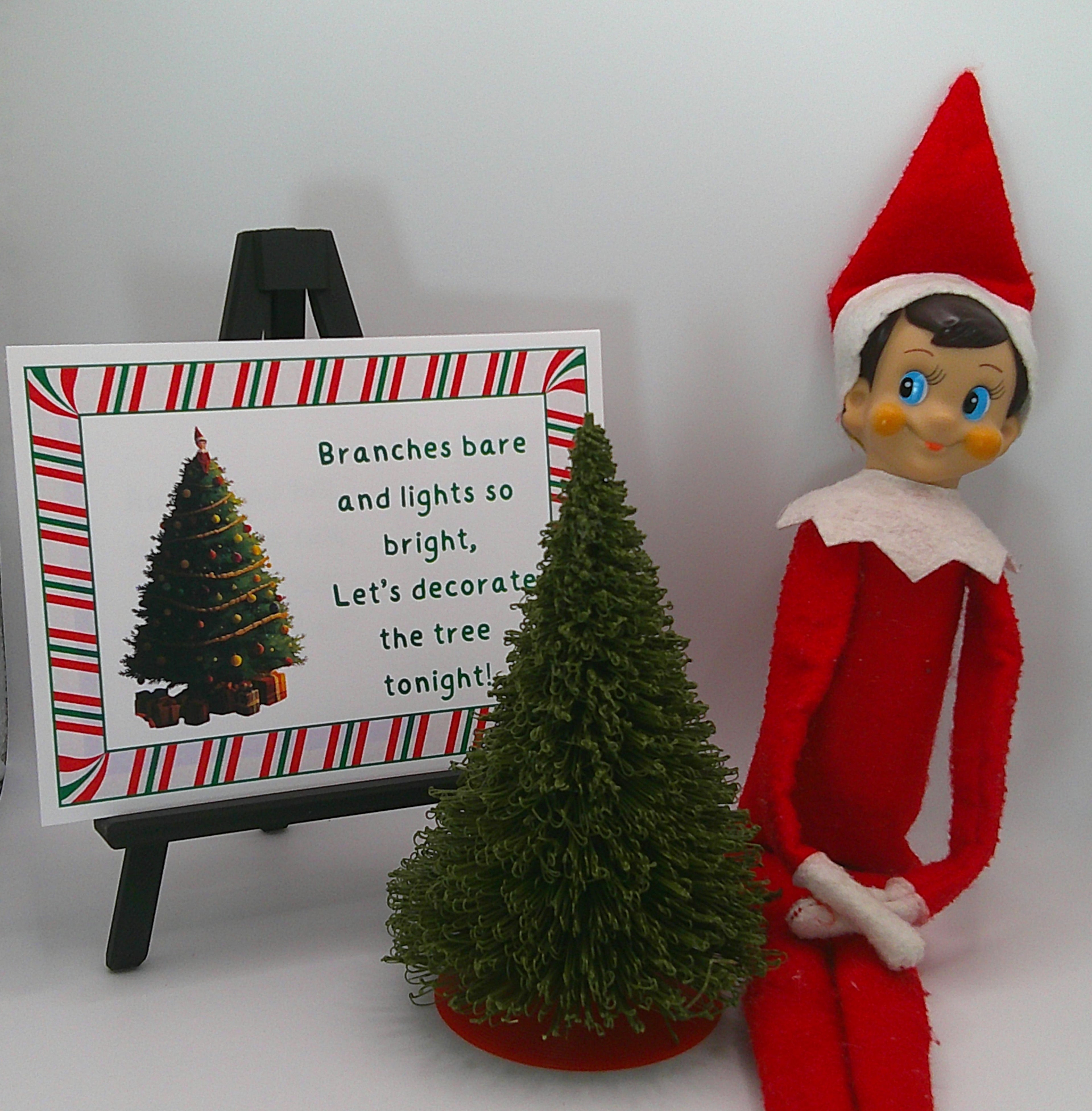 Elf on the Shelf with a Christmas tree and decorative sign on a white background